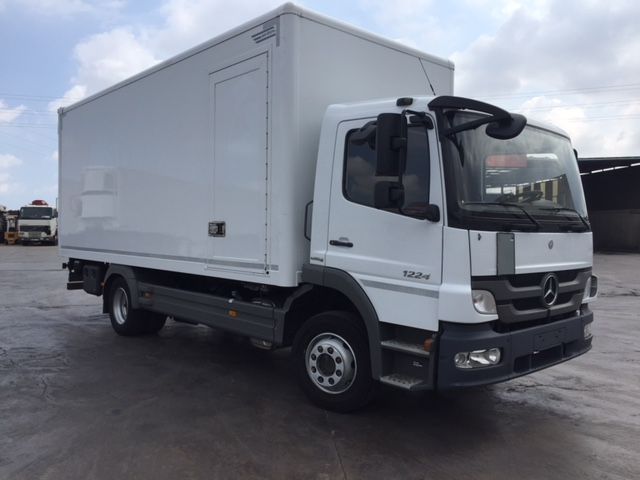 Una camioneta Mercedes blanca está estacionada en un estacionamiento.