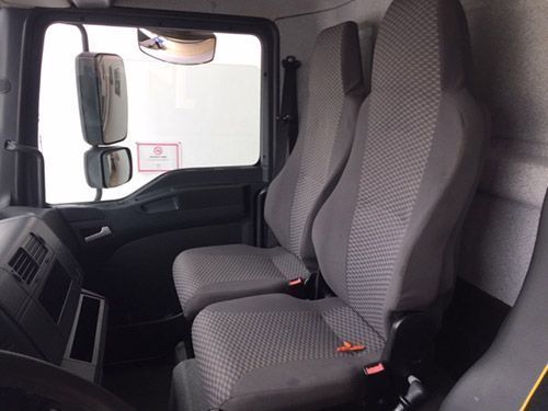 El interior de un camión con dos asientos y un volante.