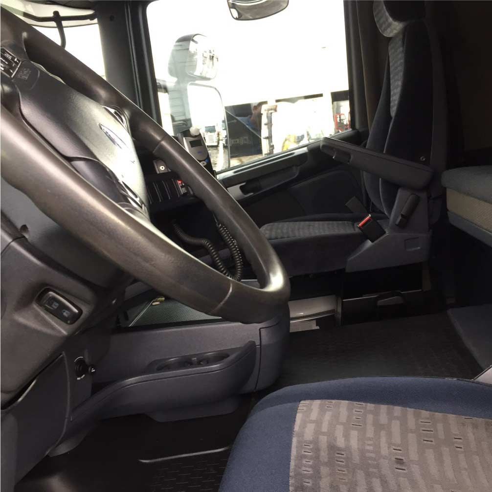 El interior de un camión con volante y asientos.