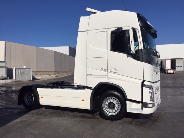 Un camión semirremolque blanco está estacionado frente a un edificio.