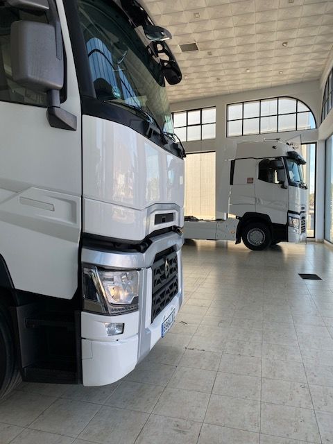Dos camiones blancos están estacionados en una habitación grande.