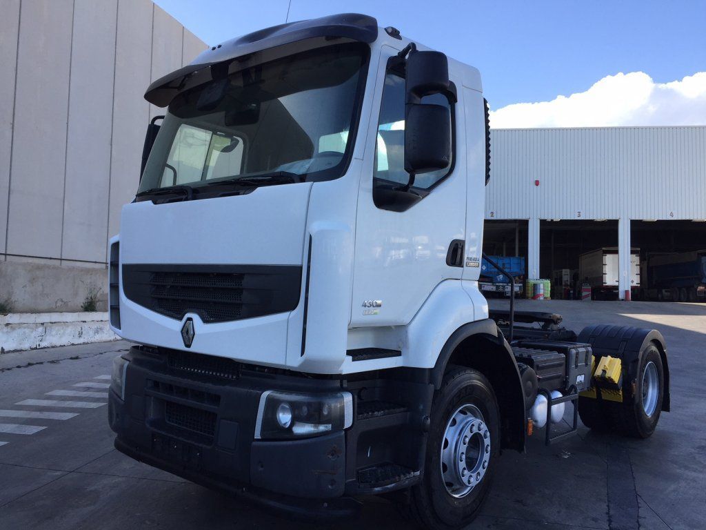 Un camión semirremolque blanco está estacionado frente a un edificio.