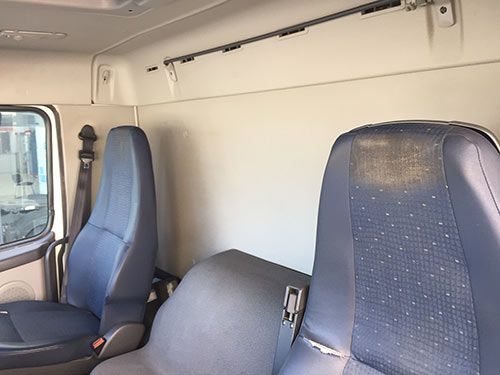 El interior de un camión con asientos azules y una pared blanca.