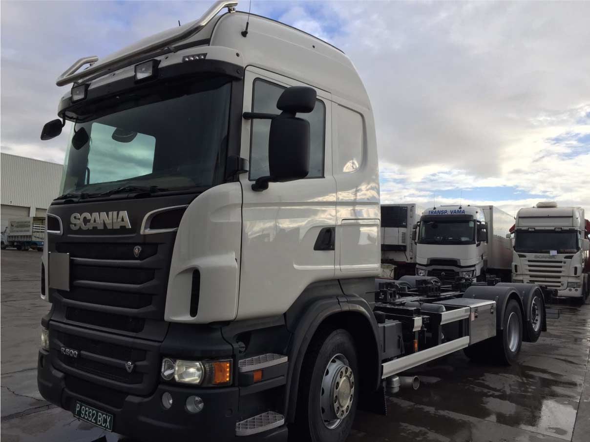 Un camión semirremolque Scania blanco está estacionado en un estacionamiento.