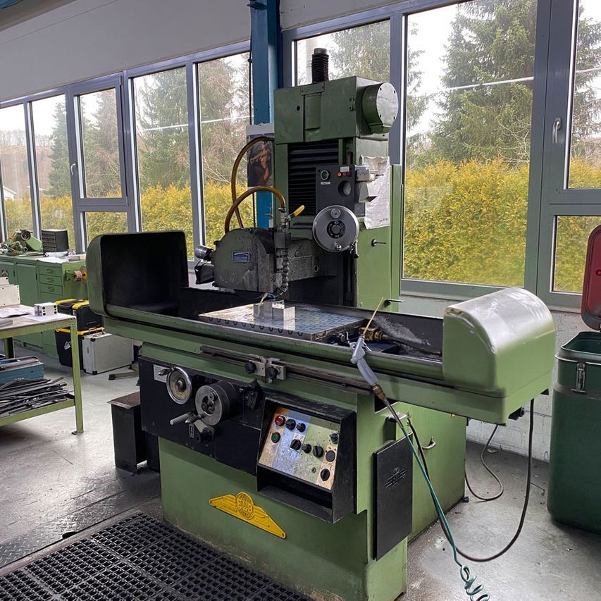 Eine grüne Maschine steht in einem Raum mit vielen Fenstern.