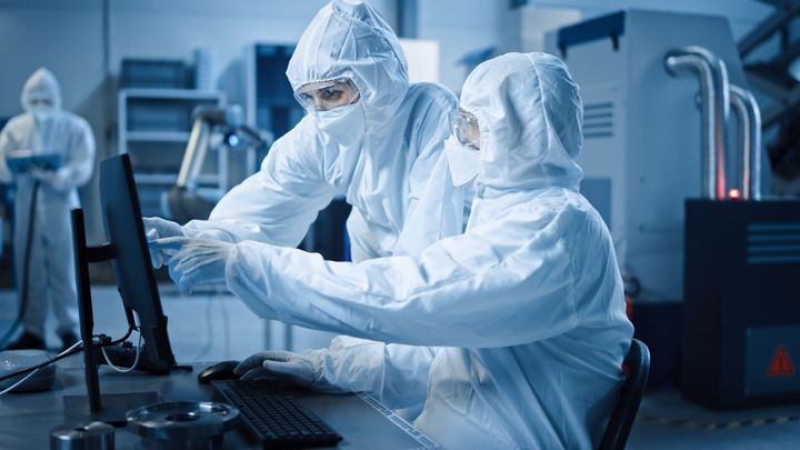 A woman in a lab coat works on a machine.