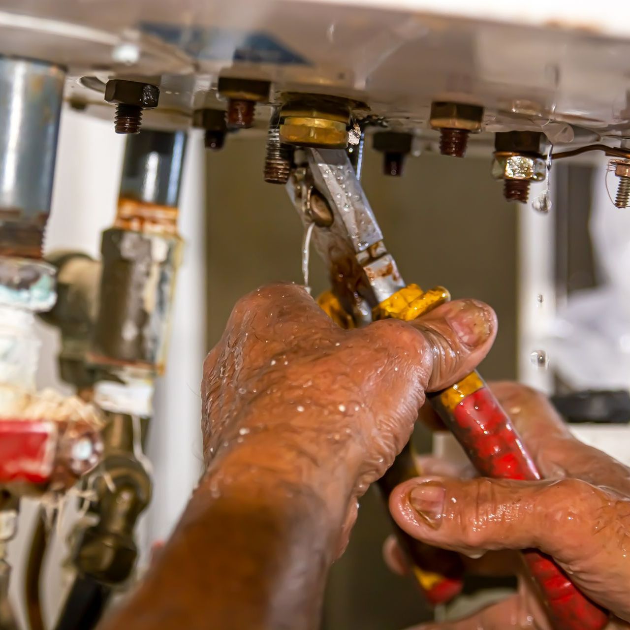Un homme intervenant sous un chauffe-eau