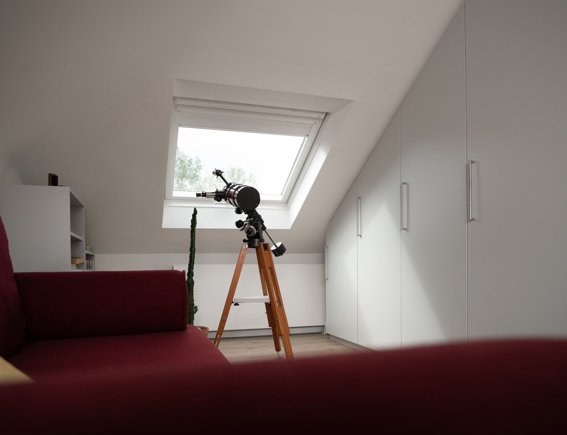 Eingerichteter Raum mit maßgeschneidertem Wandschrank, Dachfenster und Teleskop 