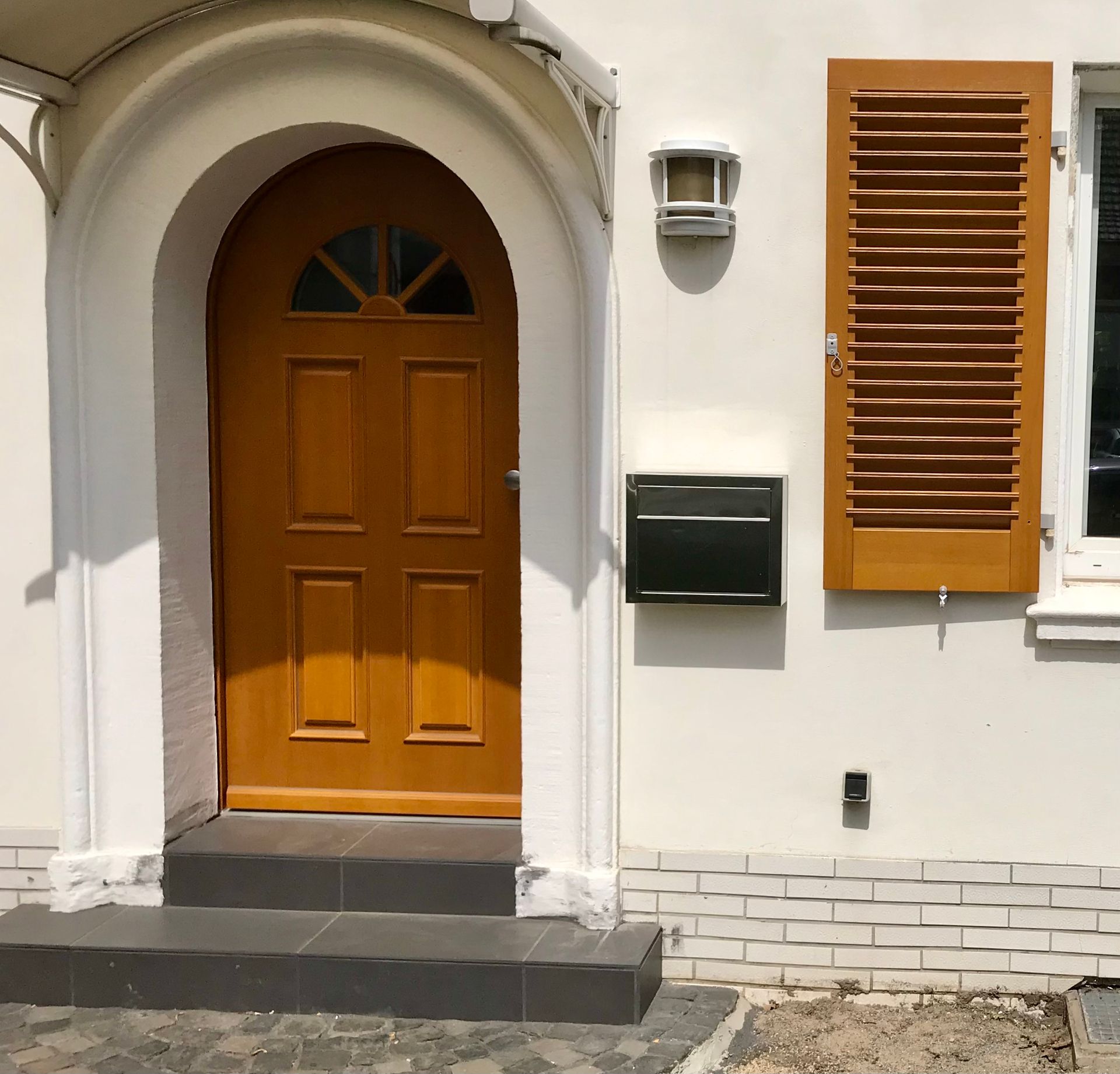 Runde braune Haustür und Fenster mit passenden Fensterläden