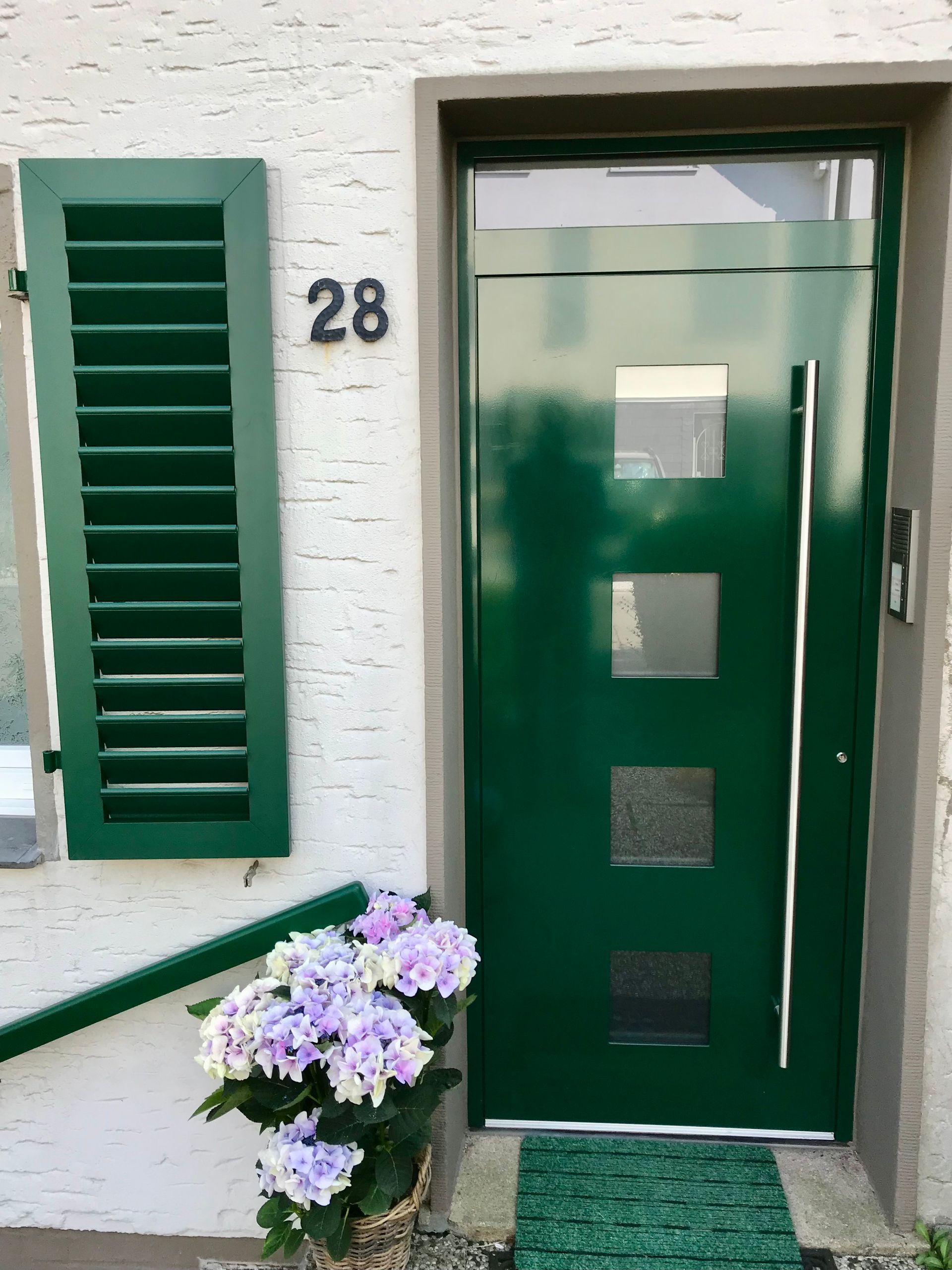 Grüne Haustür und Fenster mit passenden Fensterläden