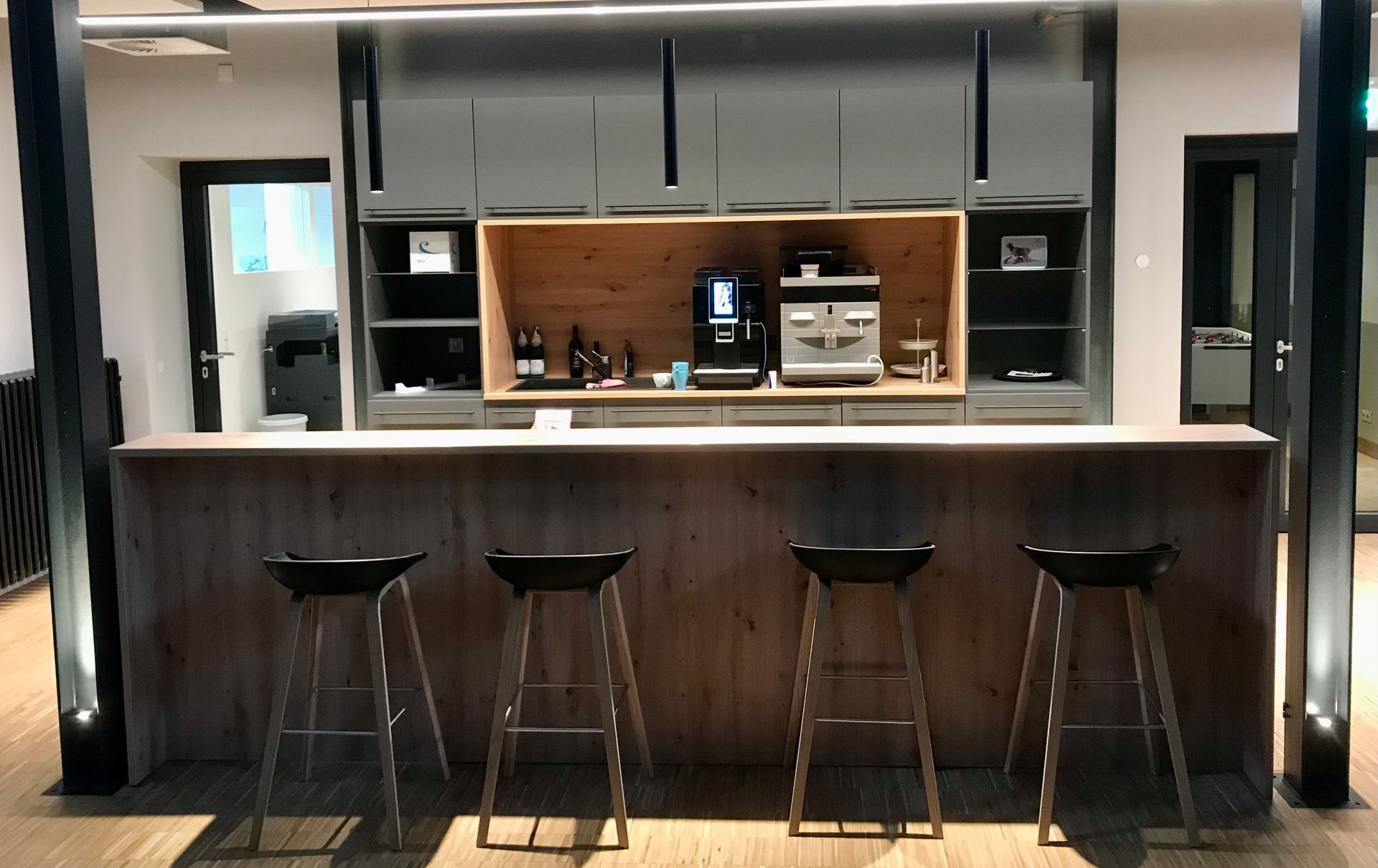 Küche mit Theke und Thekenstühlen in dunklem Grau mit hellen Holzakzenten