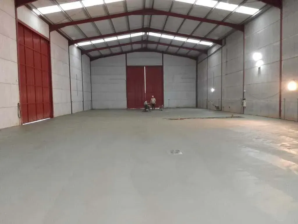 Un gran almacén vacío con puertas rojas y suelo de hormigón.