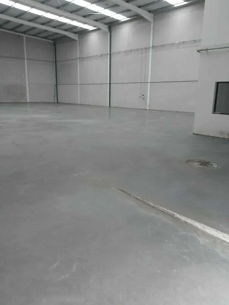 Un almacén vacío con suelo de hormigón y paredes blancas.