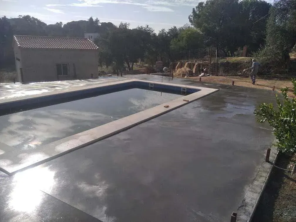Una gran piscina está rodeada por un patio de hormigón.