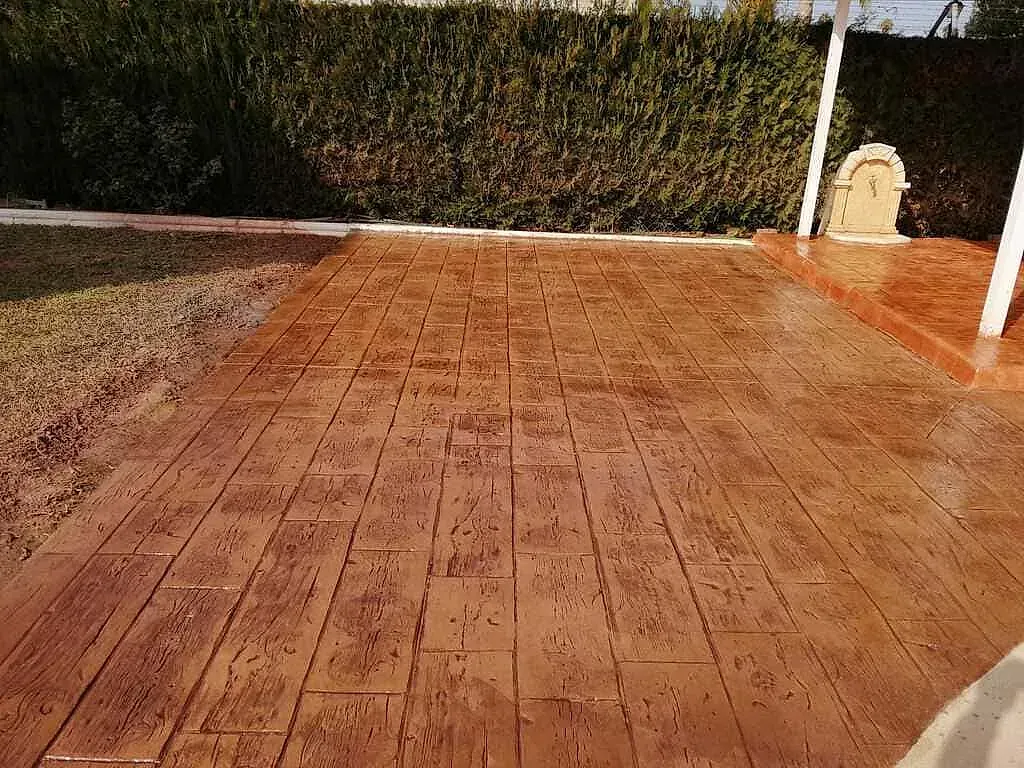 Un patio con diseño de ladrillo y una valla al fondo.