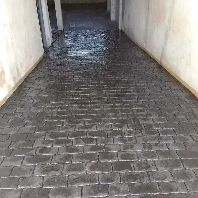 Una pasarela de ladrillos que conduce a un edificio con una pared blanca.