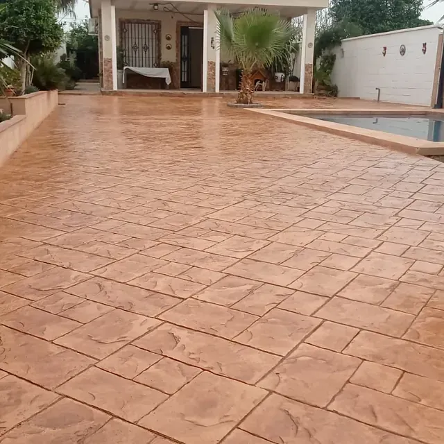 Un camino de entrada de ladrillo con una piscina al fondo.