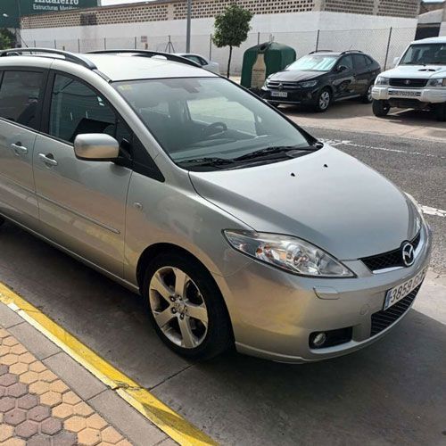 Una minivan plateada está estacionada en un estacionamiento
