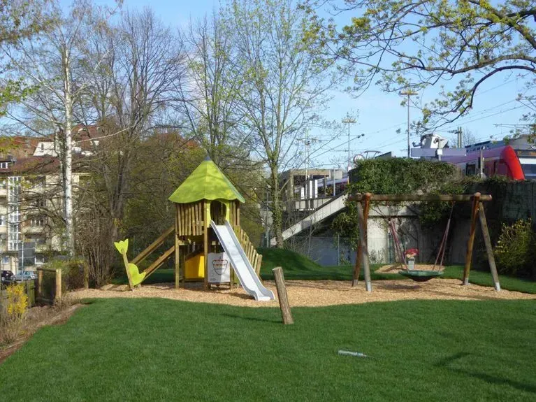 Ein Spielplatz mit Rutsche und Schaukeln in einem Park