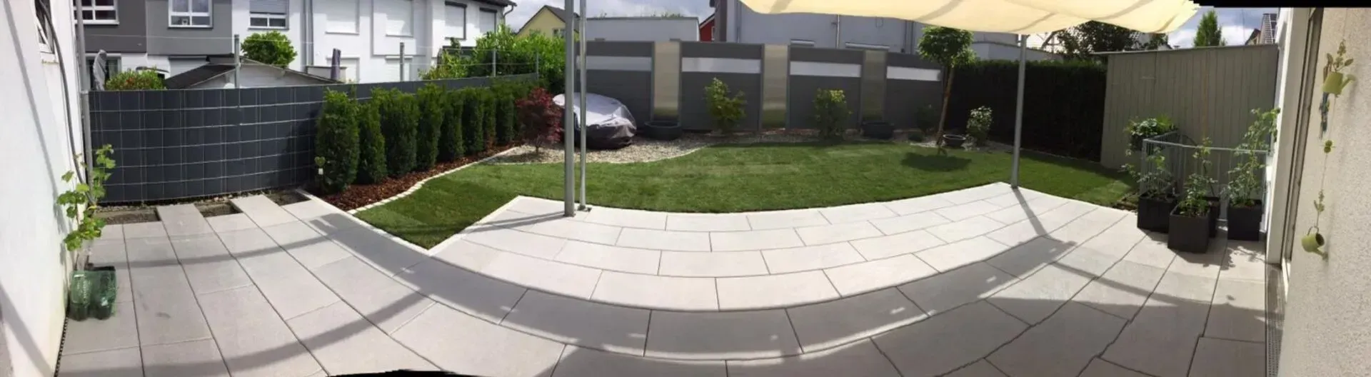 Ein Panoramablick auf einen Hinterhof mit Terrasse und Sonnenschirmen.