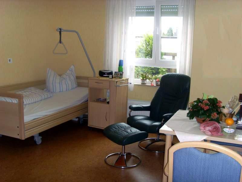 Ein Krankenhauszimmer mit einem Bett, einem Stuhl und einem Tisch