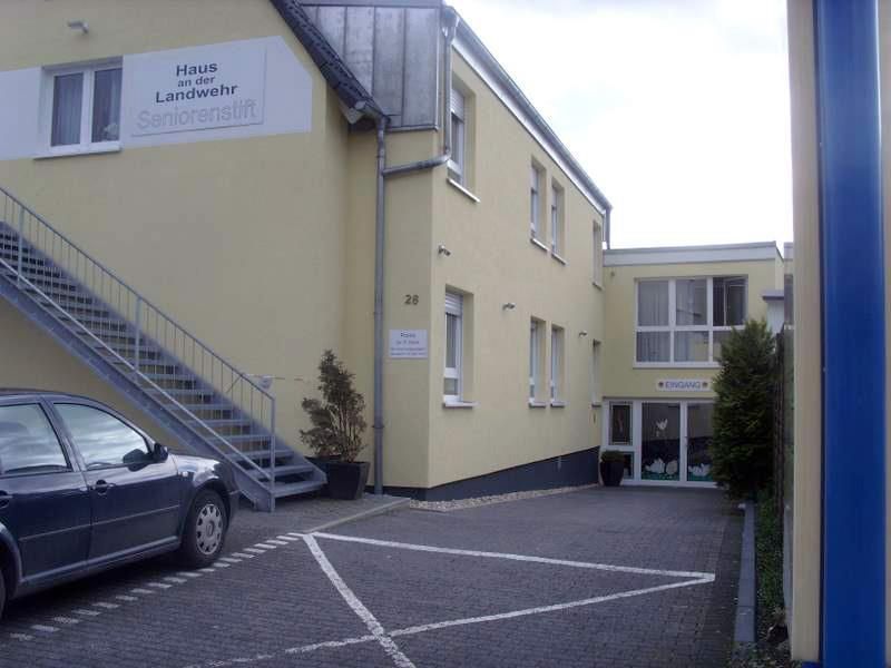 Ein Auto steht vor einem Gebäude, zu dem eine Treppe hinaufführt