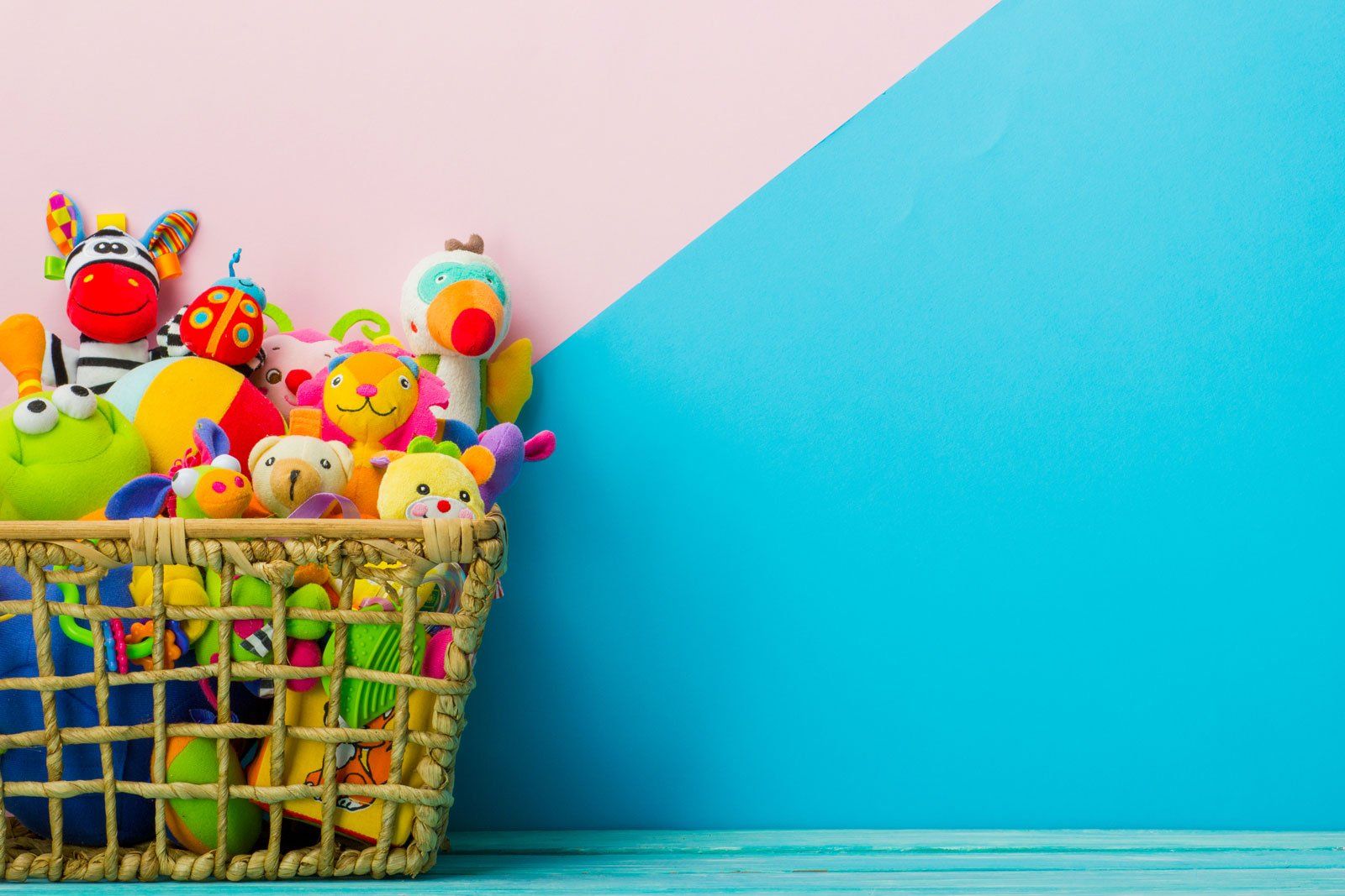 Jouets en peluche dans une corbeille sur fond rose et bleu