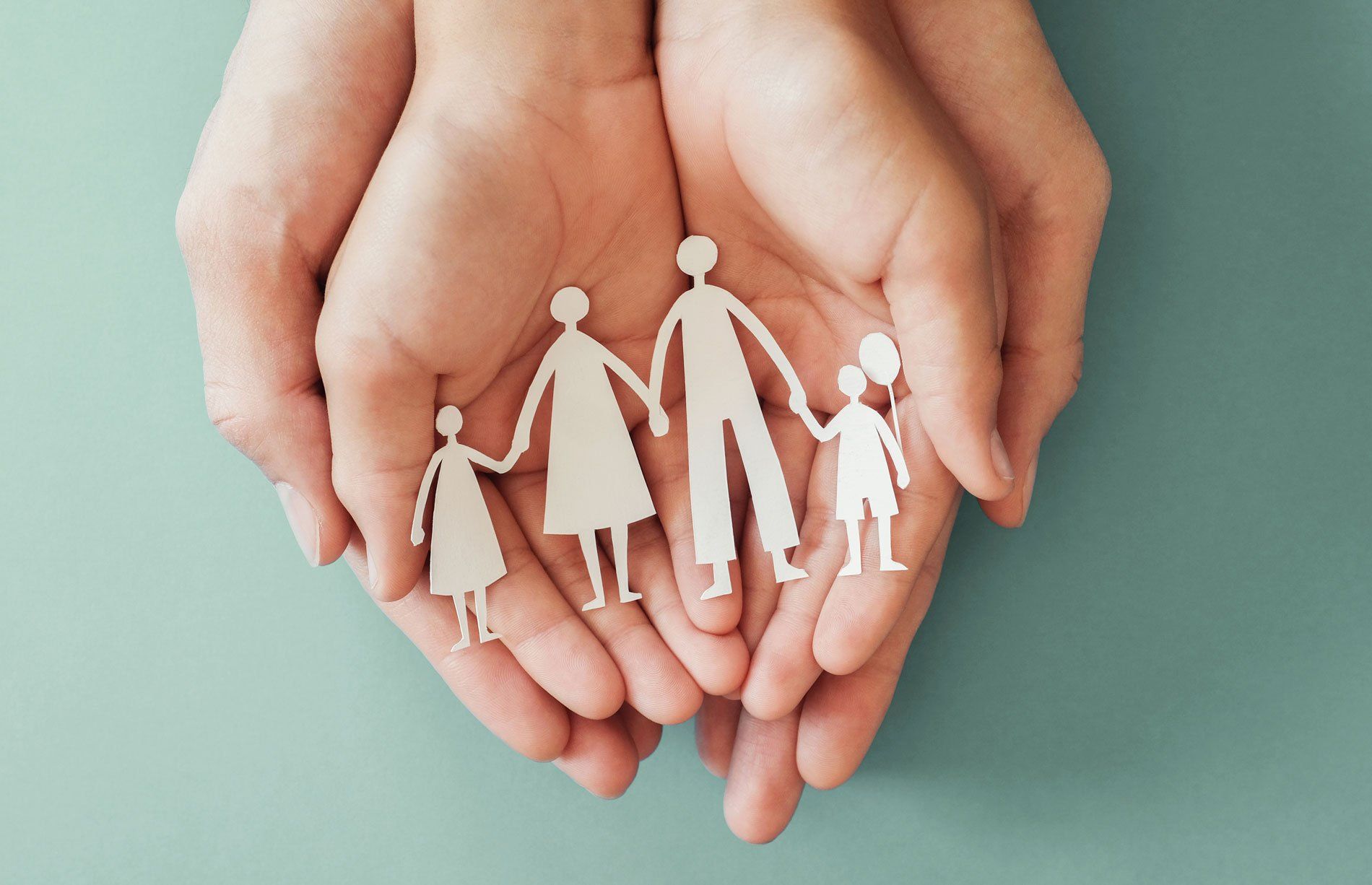 Mains d'enfant tenant la silhouette en papier d'une famille dans des mains d'adulte