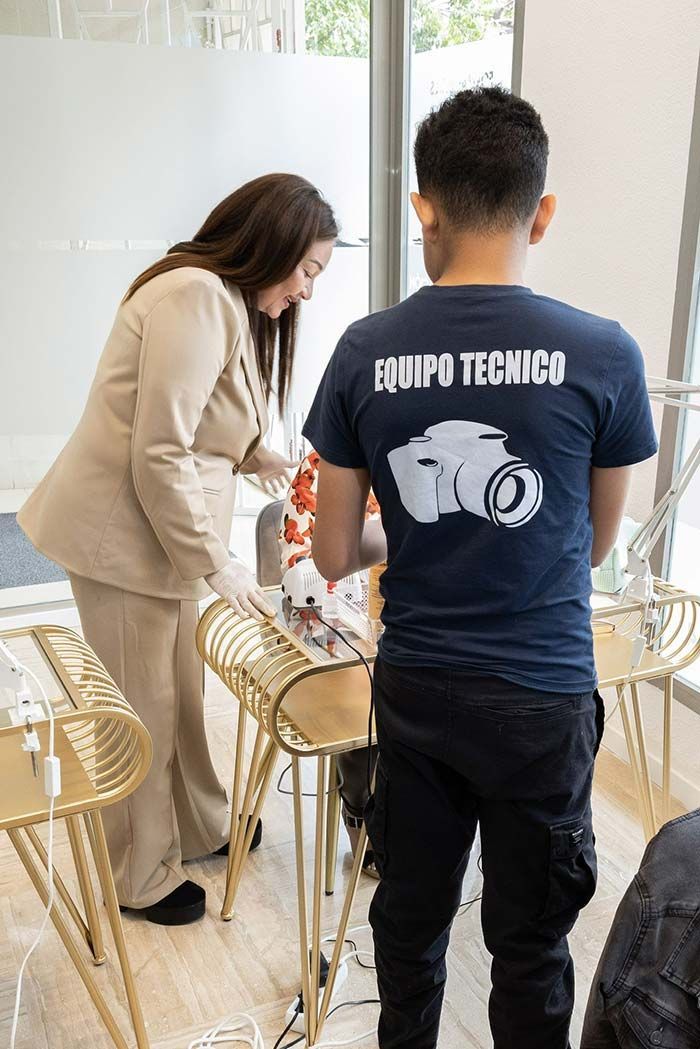 Un técnico con camisa azul marino y un profesional con traje beige trabajan en mesas doradas en un interior luminoso y moderno.
