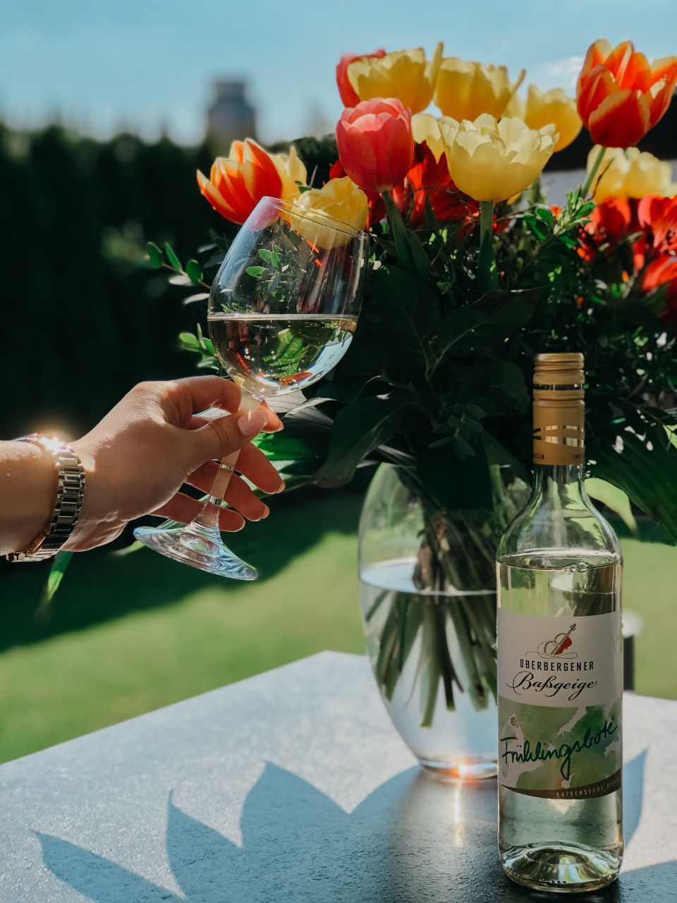 Rot-gelber Blumenstrauß mit Weinflasche und Weinglas