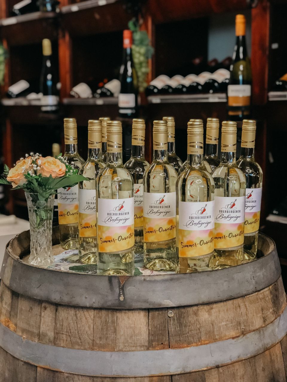 Weißweinflaschen auf einem Holzfass