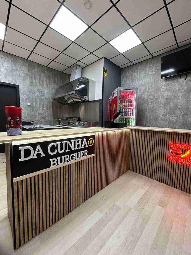 Un restaurante con un mostrador de madera y un cartel que dice da cunha burger.