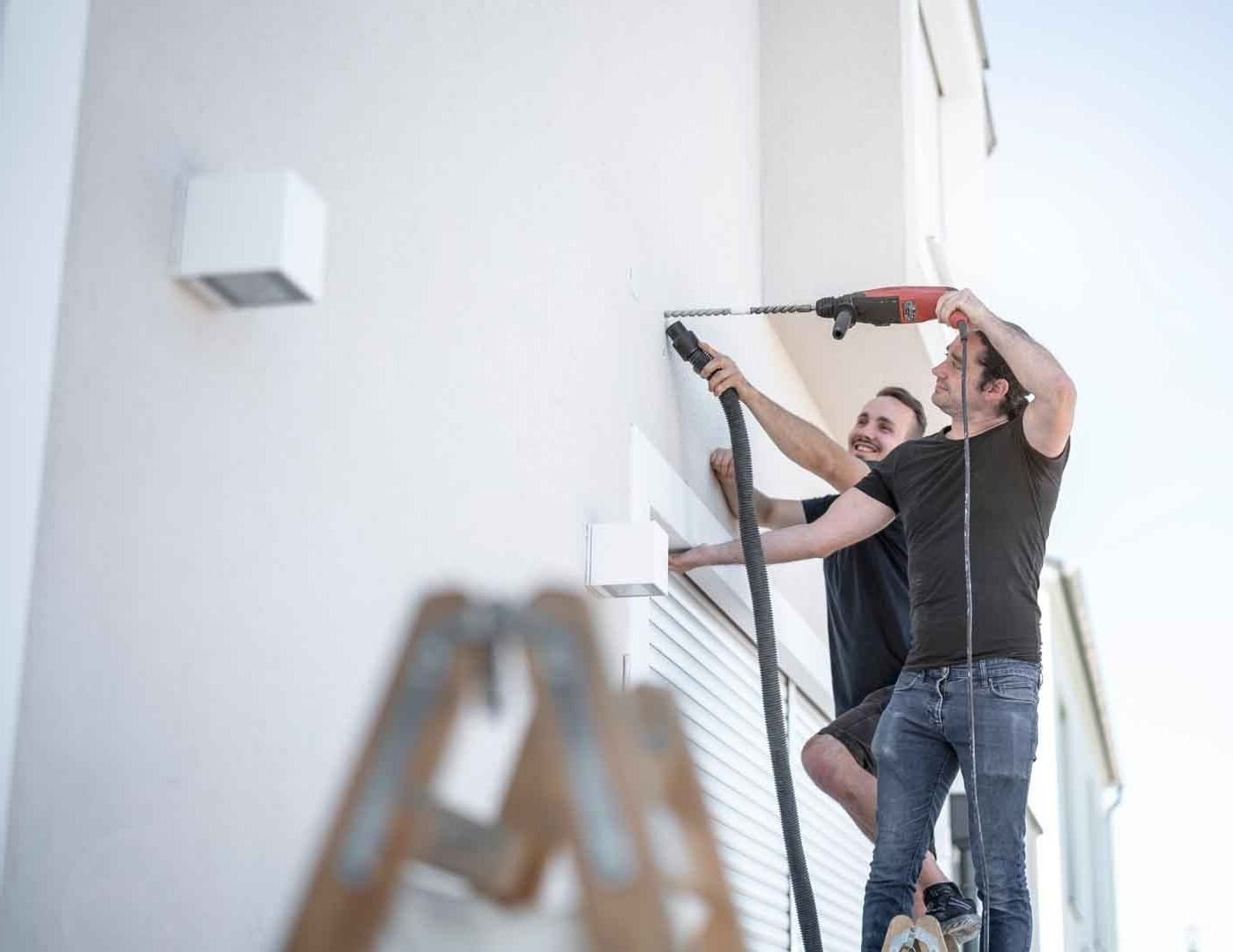 Deux hommes sur un échelle devant un volet roulant