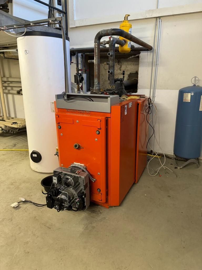 Orangefarbene Heizung und weißer Warmwasserbereiter im Hauswirtschaftsraum.
