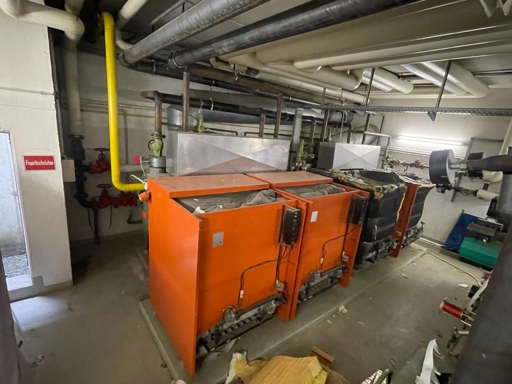 Orangefarbene Heizungsanlage in einem Hauswirtschaftsraum mit Rohren.