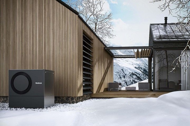 Eine moderne Hütte mit einer Wärmepumpe im Freien in einer verschneiten Berglandschaft.