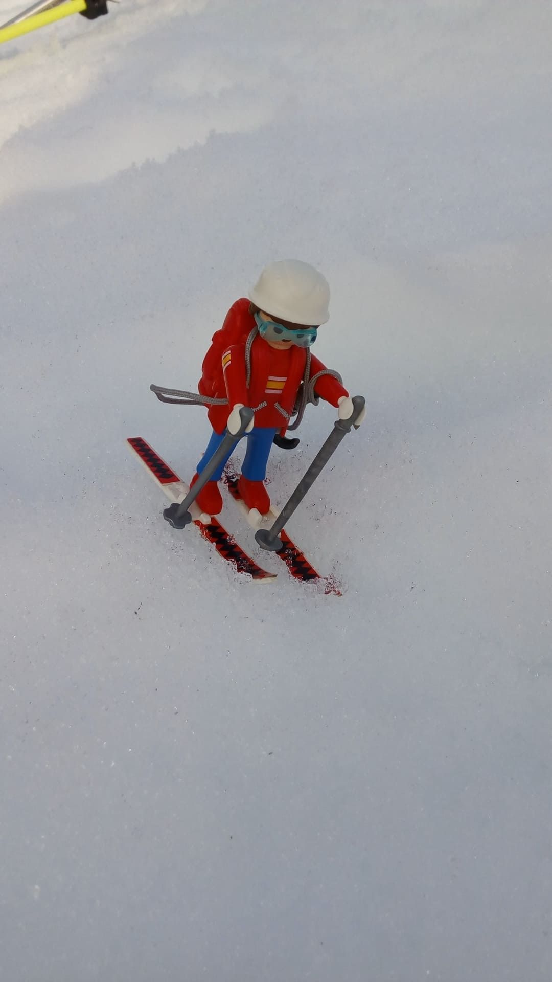 Niño esquiando cuesta abajo con una chaqueta roja y pantalones azules en una pista nevada