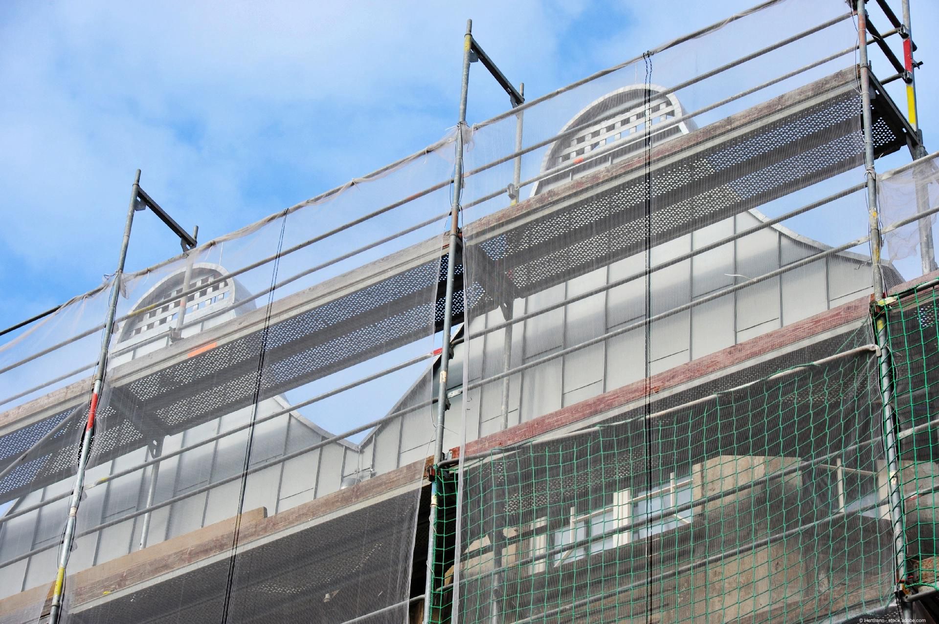 Gerüst mit Sicherheitsnetz bei der Sanierung eines denkmalgeschützten Gebäudes mit kunstvoller Attika