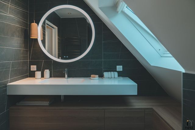 Salle de bains sous combles avec vasque et miroir lumineux