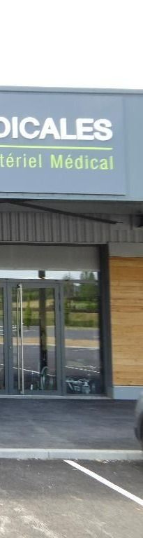 Extérieur d'un magasin de fournitures médicales avec des portes vitrées et une enseigne indiquant Matériel Médical.