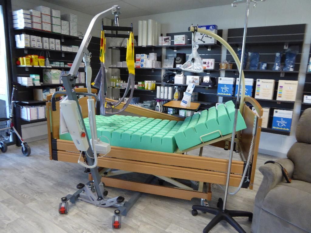 Lit d'hôpital, matelas antiescarres et support pour perfusion intraveineuse dans un magasin de fournitures médicales.