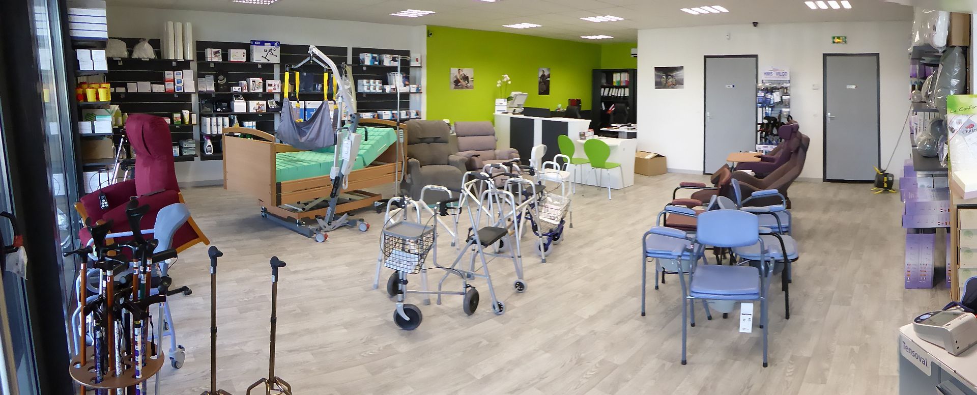 Dans un magasin de fournitures médicales, divers équipements tels que des fauteuils et des déambulateurs sont exposés.
