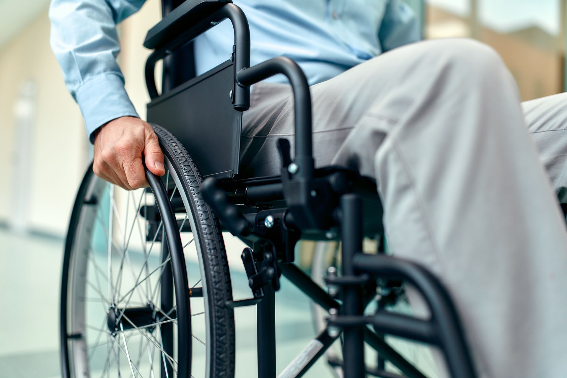 Un homme assis dans un fauteuil roulant, à l'intérieur, tient le volant.