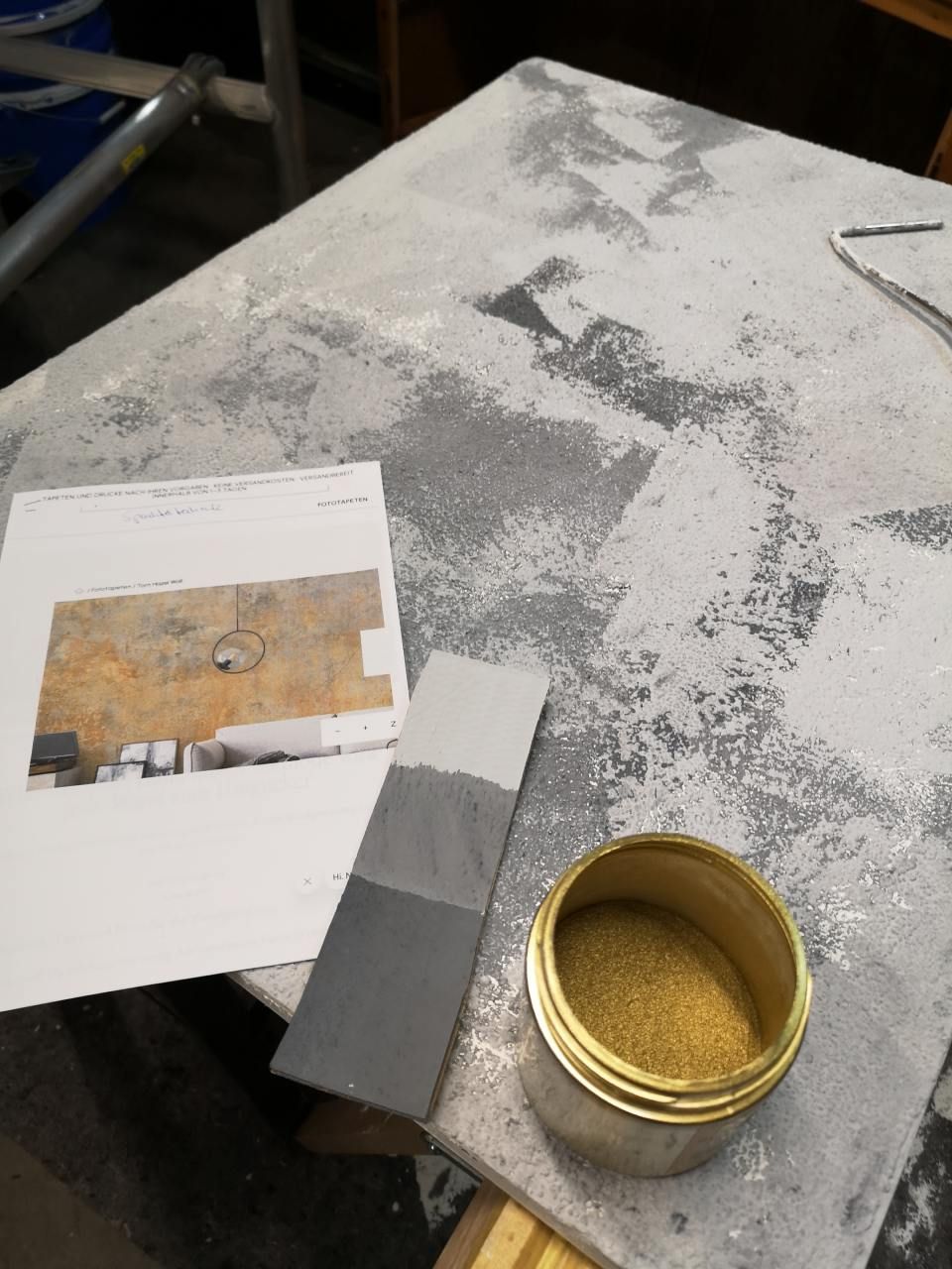 Ein Glas mit Goldpulver steht auf einem Tisch neben einem Stück Papier, MALEN TAPEZIEREN, JAMES MARTIN