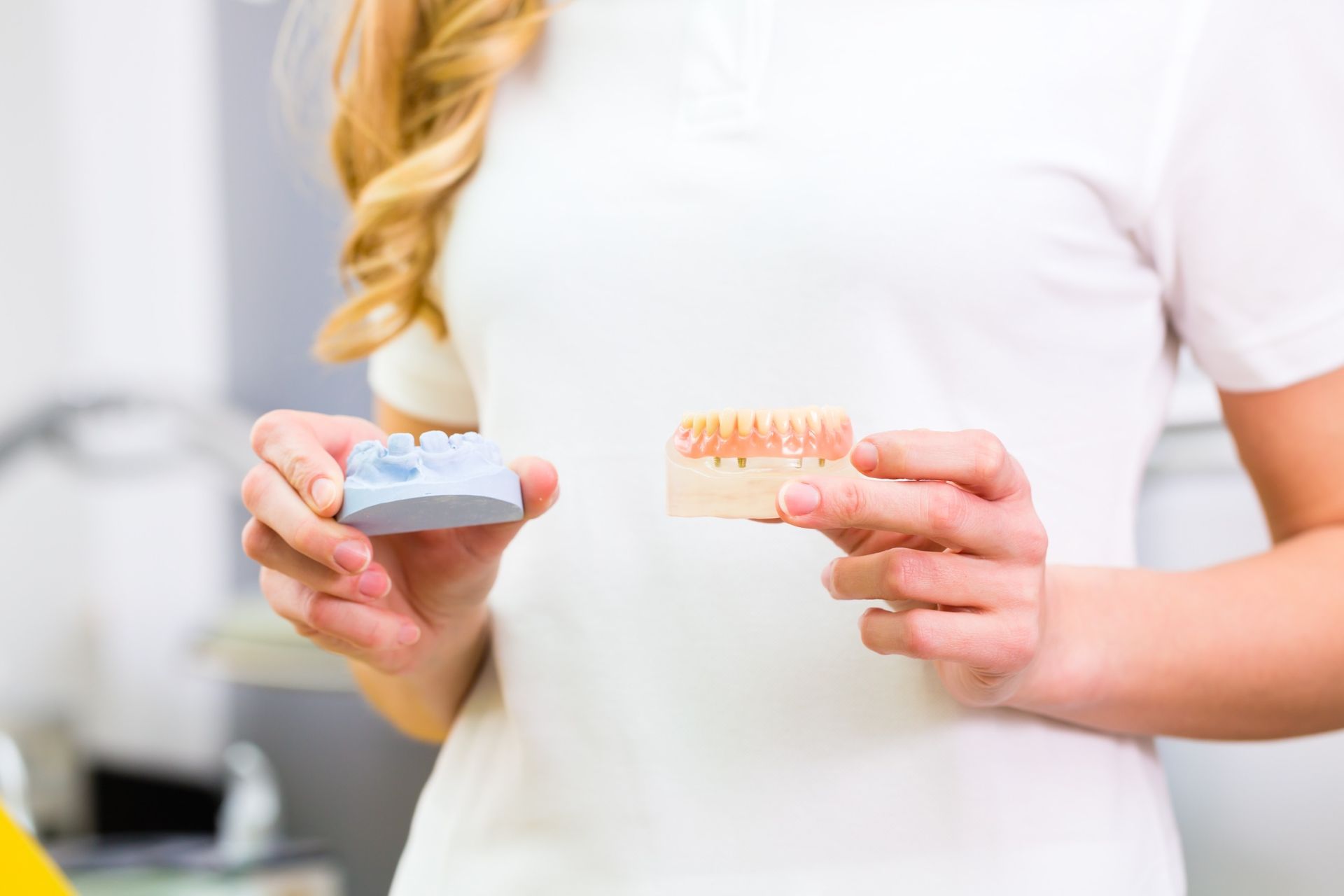 Una mujer sostiene un modelo de dientes en sus manos.