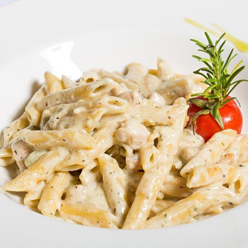 Eine Schüssel Nudeln mit einer Tomate und Rosmarin darauf.