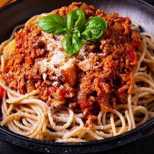 Eine Schüssel Spaghetti mit Fleischsoße und Basilikum darauf