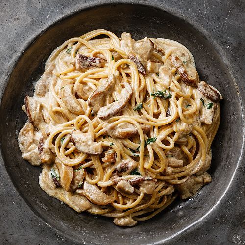 Ein Teller Spaghetti mit Pilzen und Soße auf einem Tisch.