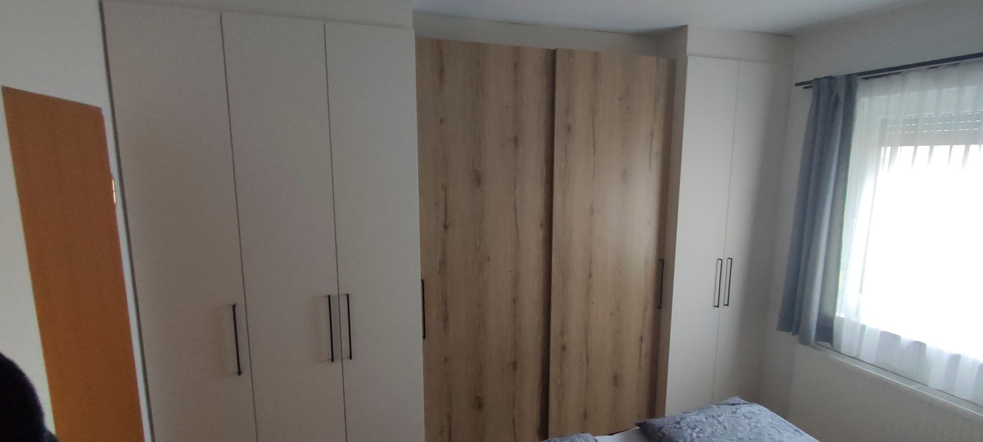 Ein Schlafzimmer mit Bett, Kleiderschrank und Fenster.