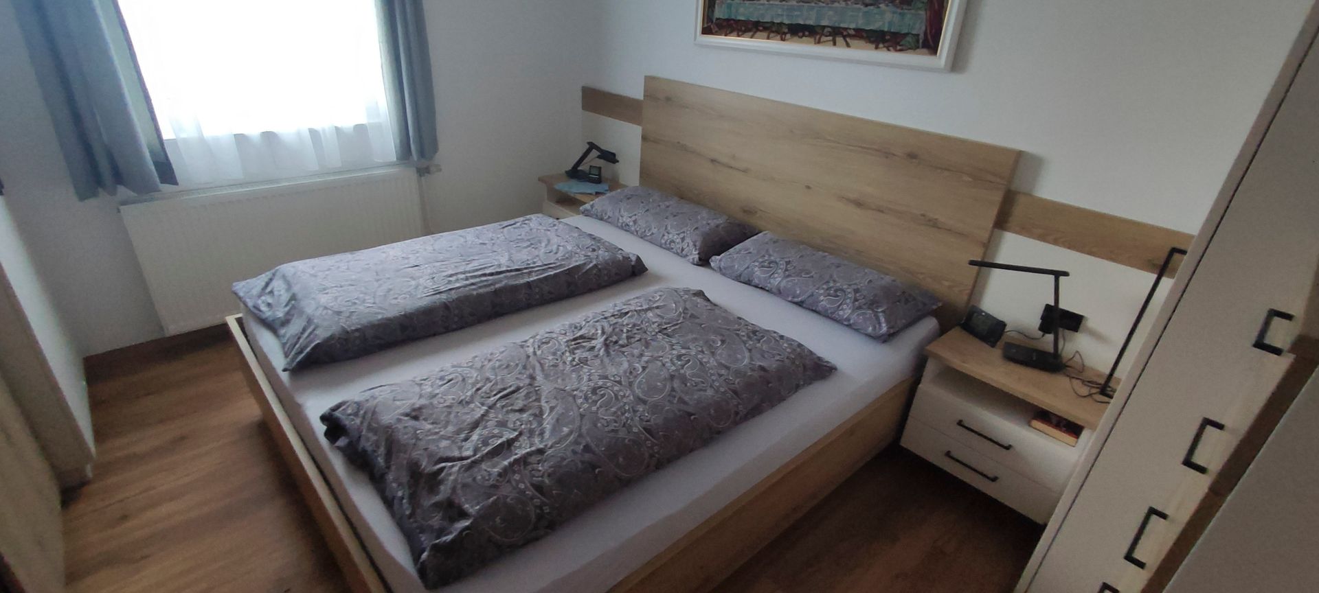 Ein Schlafzimmer mit zwei Betten, einem Nachttisch und einem Fenster.